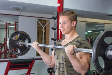 Man performing barbell curl at the gym