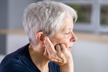 Person touching plugged ear while resting during workout.