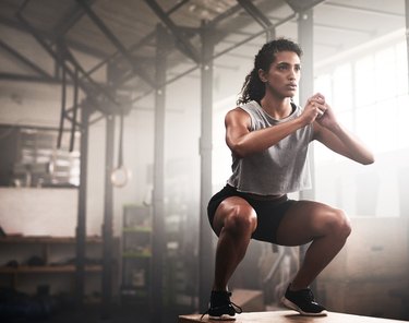 woman squating in gym doing quick plyometric workout