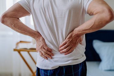 Close up of older adult rubbing their back after waking up stiff