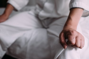 close view of a person's hands gripping the bedcovers because they woke up shaking