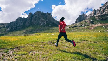 adult ultra marathoner running outside with mountains on the background experiencing bruised legs after working out