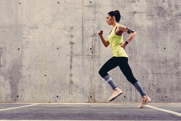 A young adult wearing a yellow tank top and black leggings jogging outside whose lungs hurt after running