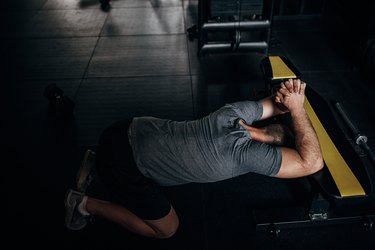 person with hairy forearms does the prayer stretch on a bench to loosen tight shoulder