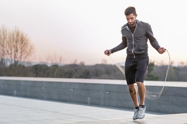 Mid adult man, outdoors, skipping with skipping rope