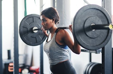 Person with a barbell on their back as part of a full-body barbell workout.