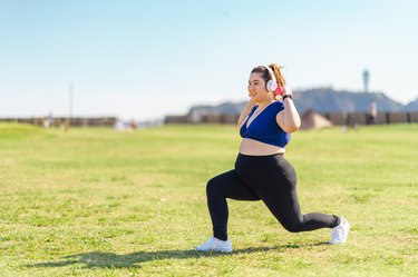 Young female athlete doing muscle trainings with dumbbells at public park