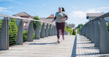 Person wearing a gray T-shirt and purple leggings running outside